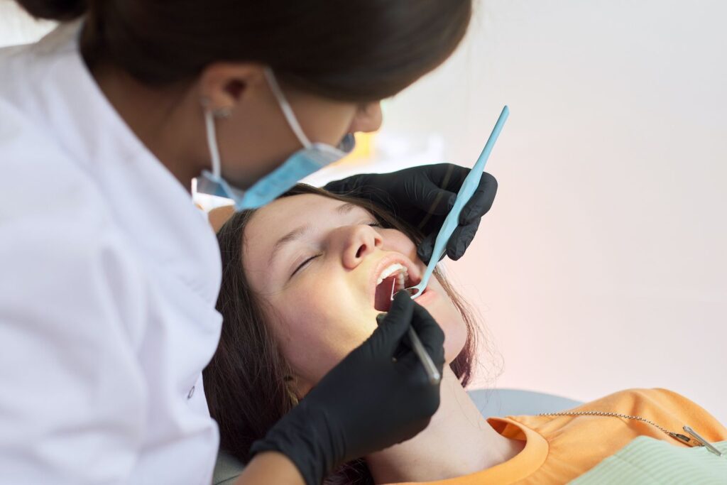 dentist treating teeth to a patient sitting in dental chair using professional equipment dental cleaning preventative dentistry dentist in Towson Maryland